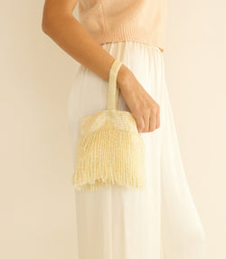 Person holding a champagne handbag against a plain background