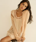 Woman wearing a peach lace nightgown with a matching cardigan against a plain background