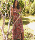 Woman in a floral dress standing among trees in a garden