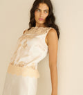Woman wearing a white lace top against a plain background
